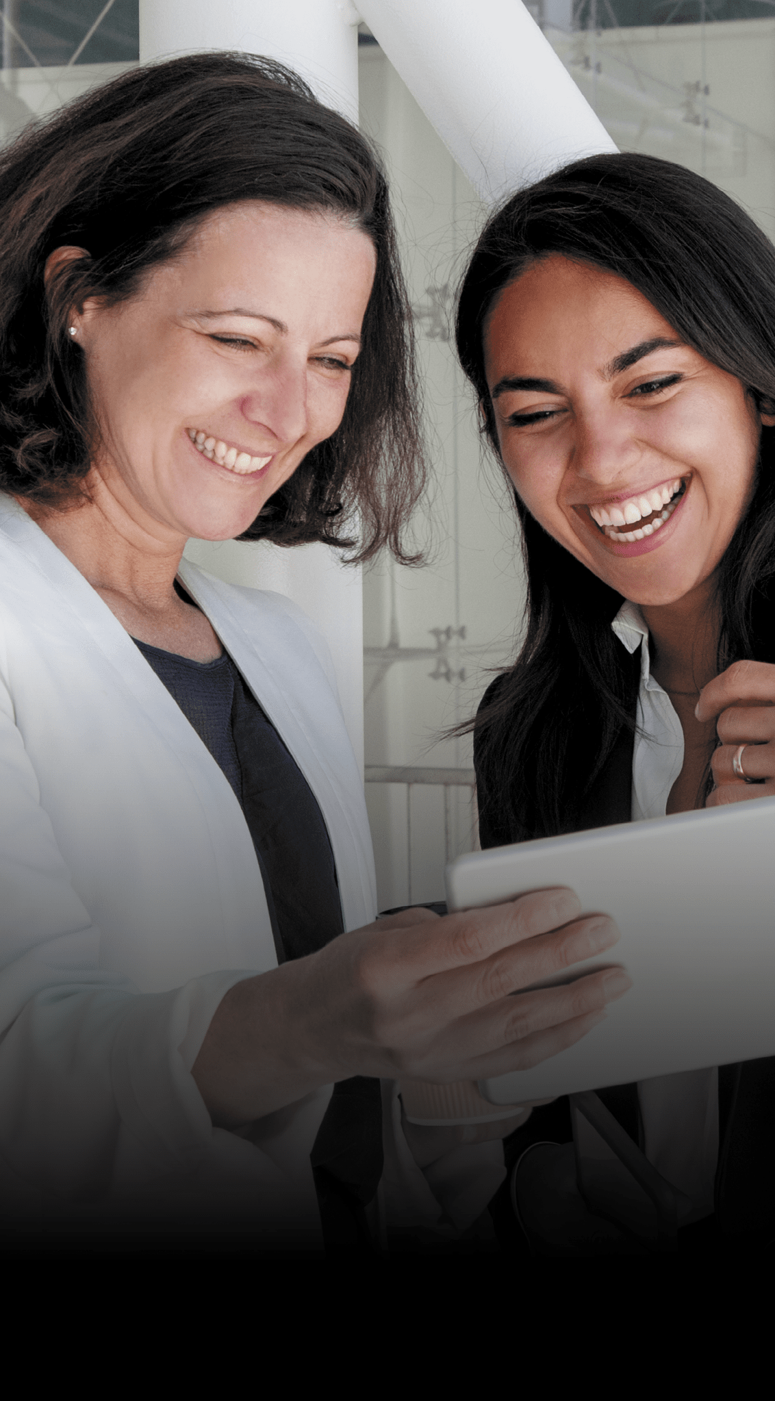 duas colaboradoras alegres a concultar um ipad